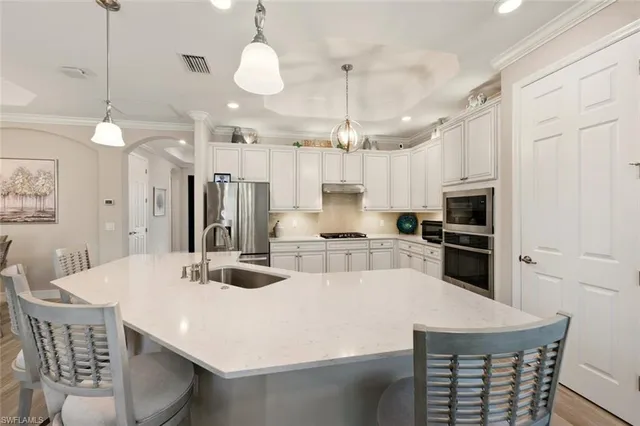 a kitchen with stainless steel appliances kitchen island granite countertop a stove a refrigerator a kitchen island a sink and a refrigerator