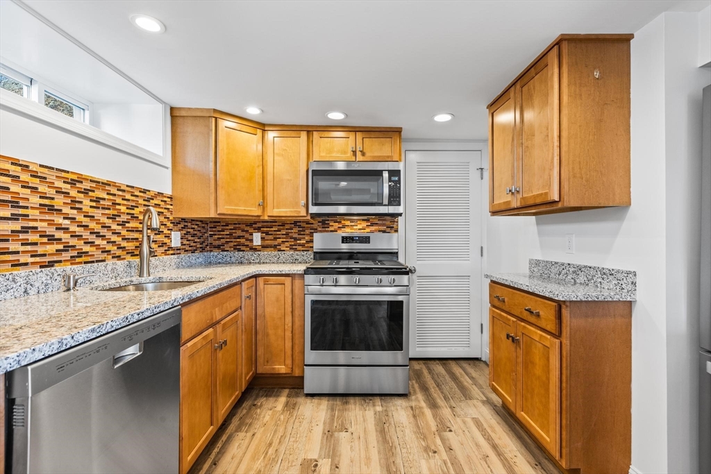 a kitchen with stainless steel appliances granite countertop a stove a sink and a microwave