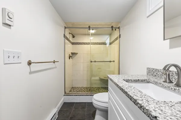a bathroom with a granite countertop sink toilet and shower