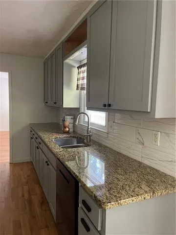 a kitchen with granite countertop a sink a stove and cabinets