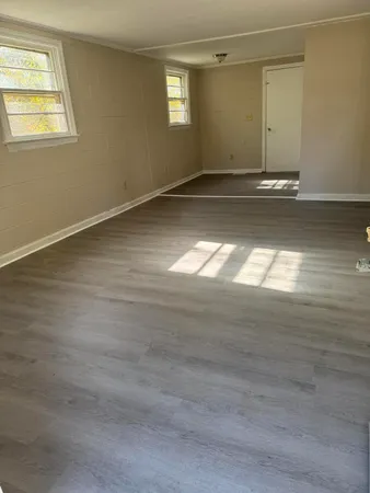 a view of an empty room with window and wooden floor