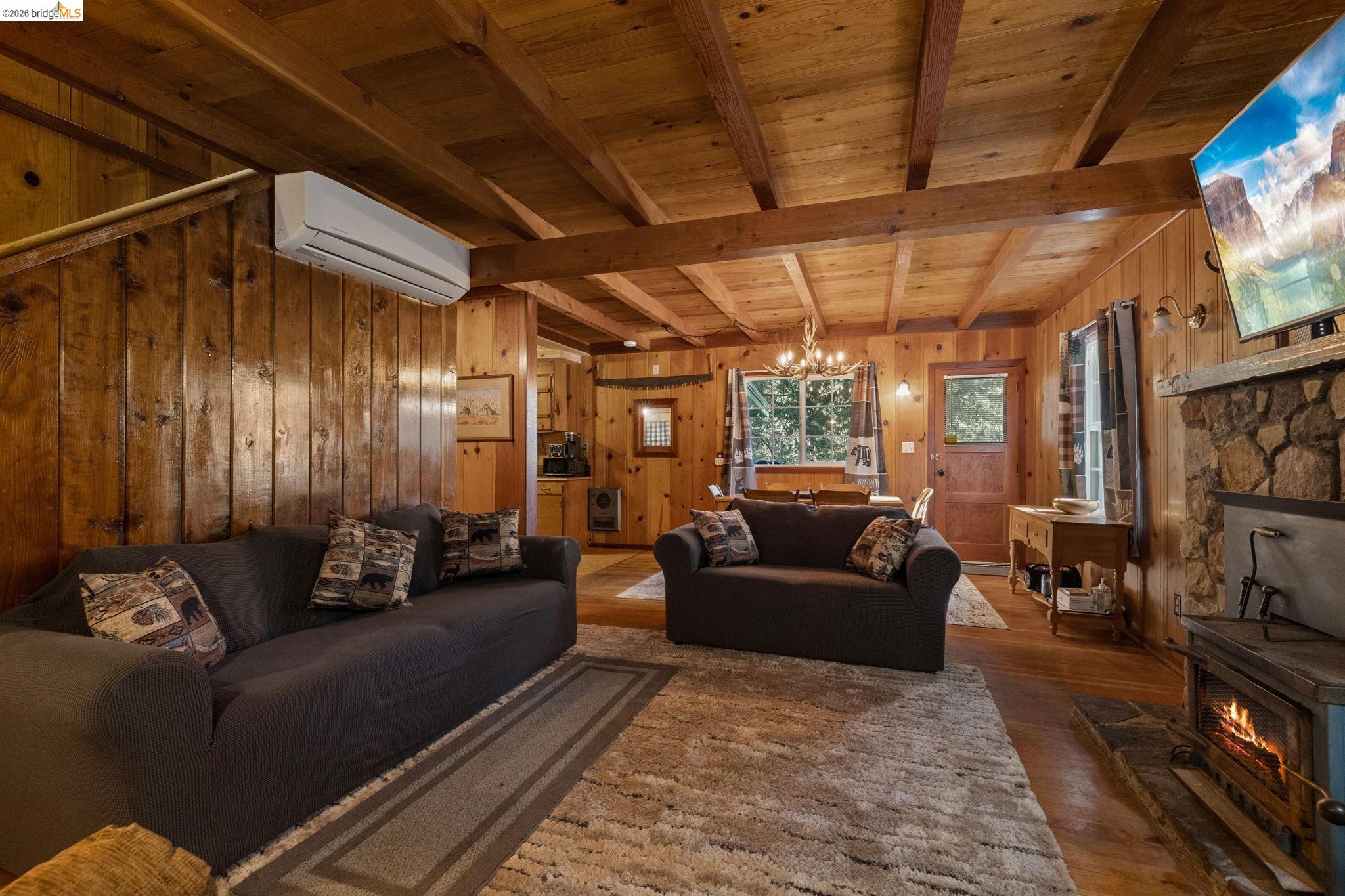 26175 Janice Way Long Barn, CA 95335 - Photo 3 of 23 Living room with wood walls, hanging lights, a wood ceiling with exposed beams, and wood finished floors