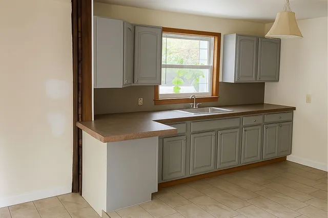 a kitchen with a sink a stove a refrigerator and white cabinets with wooden floor