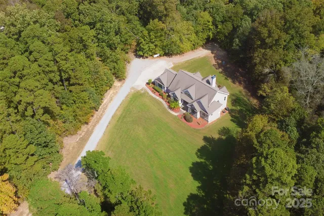 a aerial view of a house with swimming pool and large trees