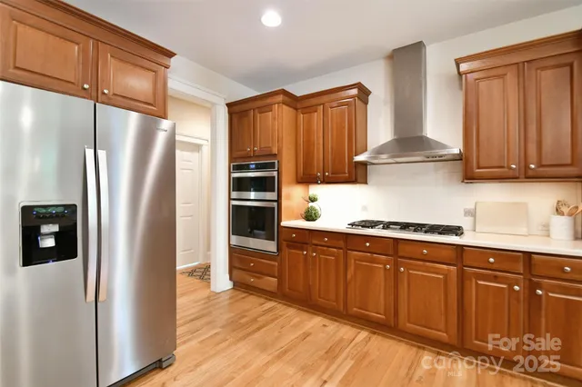 a kitchen with stainless steel appliances granite countertop a refrigerator a sink and wooden cabinets
