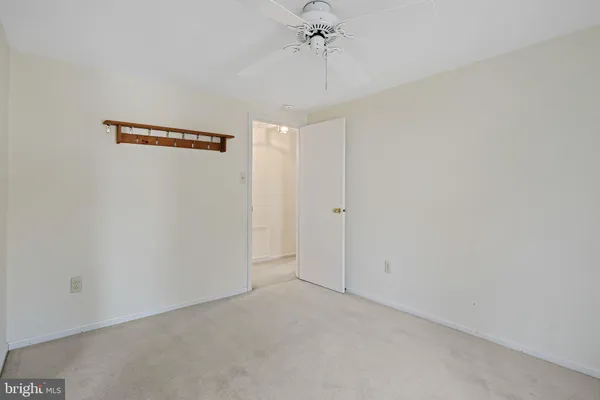 an empty room with a chandelier fan and windows