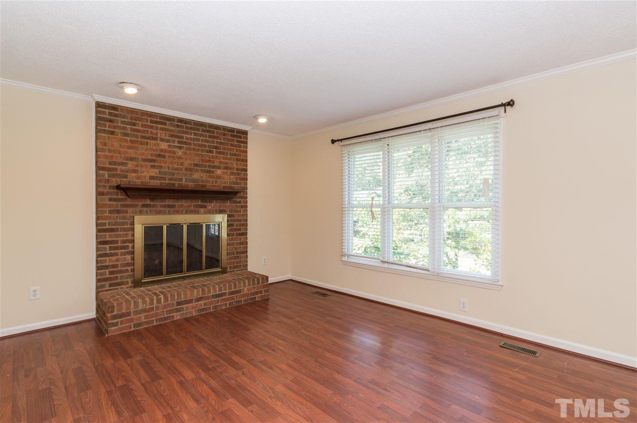6812 Glendower Road Raleigh, NC 27613 - Photo 4 of 23 an empty room with wooden floor fireplace and windows