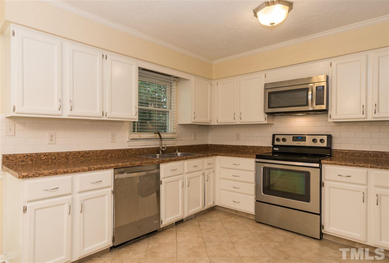 6812 Glendower Road Raleigh, NC 27613 - Photo 7 of 23 a kitchen with granite countertop white cabinets and stainless steel appliances