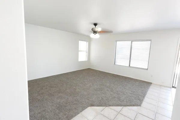 an empty room with windows and ceiling fan
