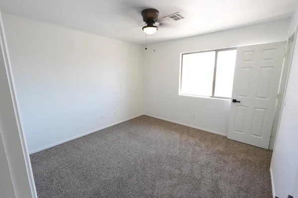 an empty room with a window and a ceiling fan
