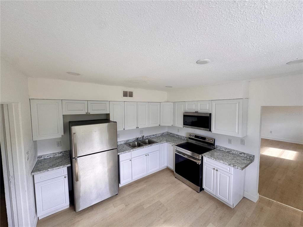 23476 Harper Avenue Punta Gorda, FL 33980 - Photo 4 of 19 a kitchen with granite countertop a refrigerator a stove top oven and a sink with wooden floor