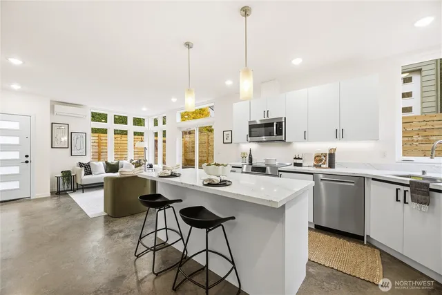 a kitchen with stainless steel appliances granite countertop a stove a sink a oven a dining table chairs and white cabinets