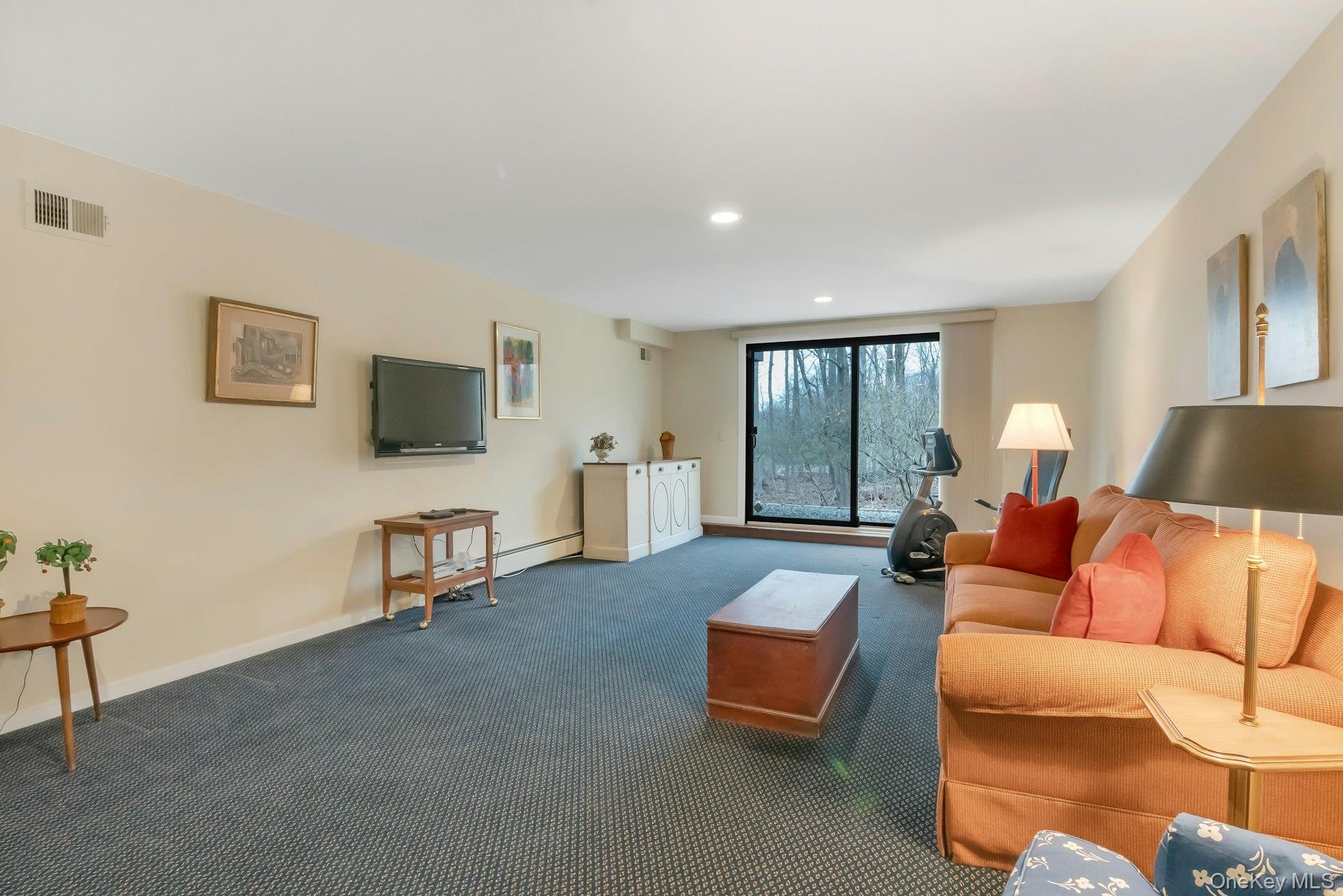 121 Law Road Briarcliff Manor, NY 10510 - Photo 36 of 48 Closer view of the walk-out Recreation Room with a wall-mounted TV and an exercise corner.