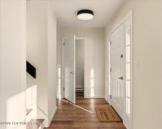 a view of a hallway with wooden floor and a bathroom
