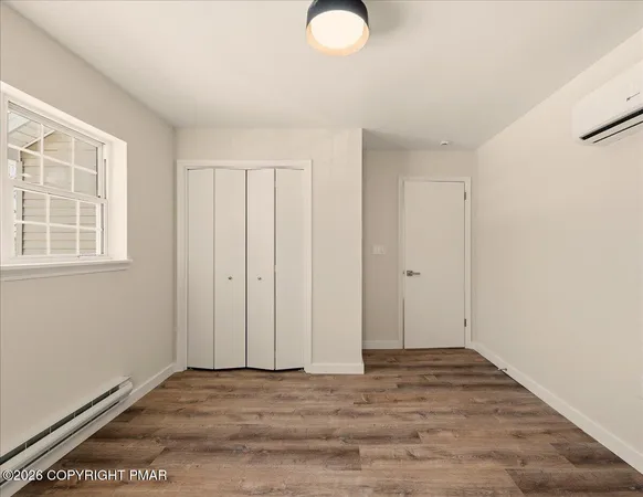 a view of an empty room with wooden floor and a window