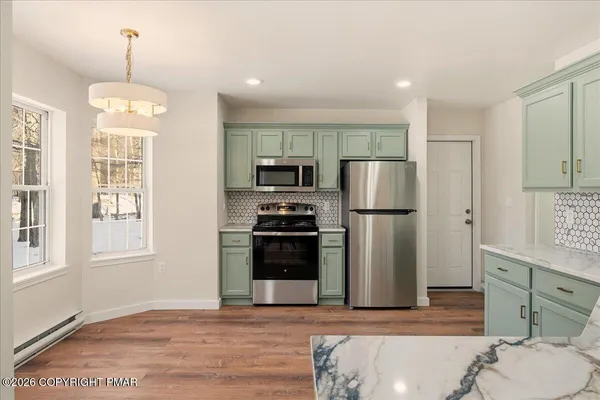 a kitchen with stainless steel appliances granite countertop a refrigerator a stove a sink and a microwave
