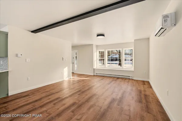 a view of an empty room with wooden floor and a window
