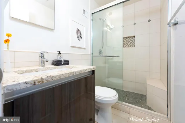 a bathroom with a granite countertop sink a toilet and shower