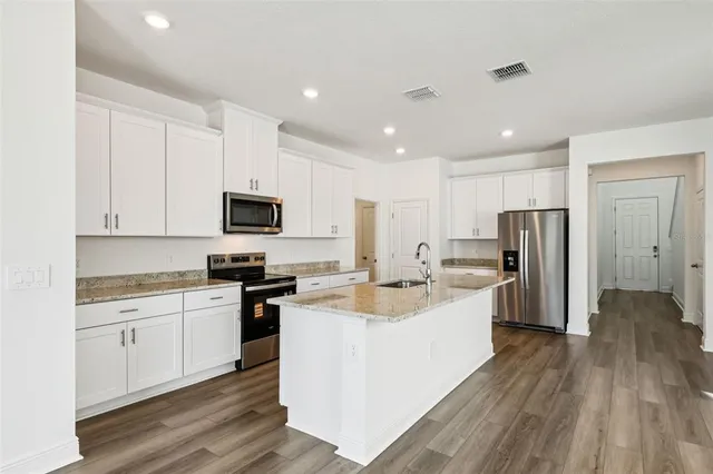 a large kitchen with a center island stainless steel appliances and cabinets
