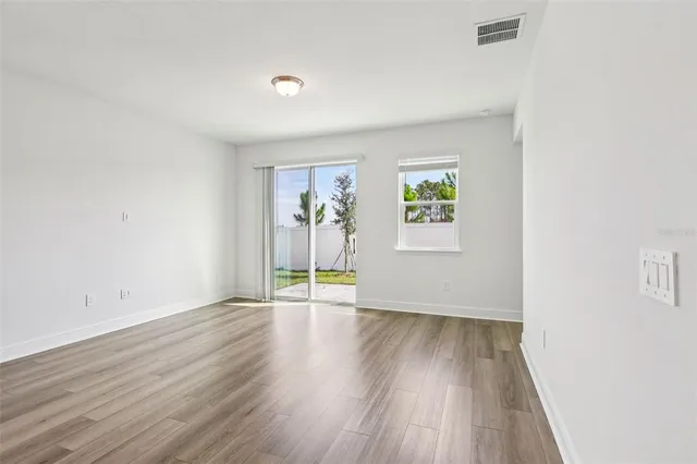 an empty room with wooden floor and windows