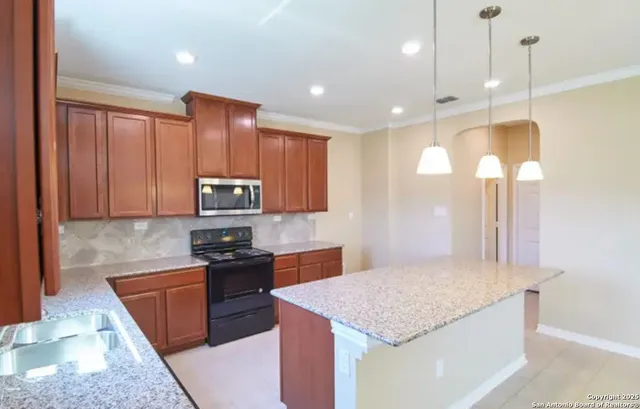 a kitchen with kitchen island granite countertop stainless steel appliances sink stove microwave and cabinets