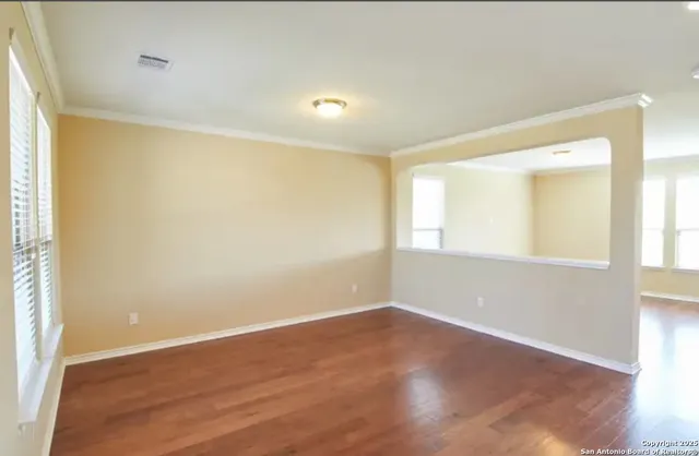 a view of empty room with wooden floor and fan