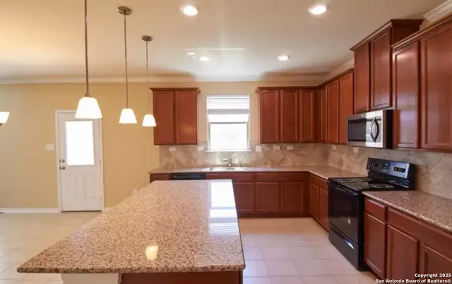 a kitchen with stainless steel appliances granite countertop a sink a stove and a wooden floor