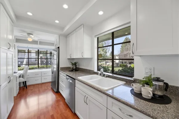 a kitchen with a sink a counter top space stainless steel appliances and windows
