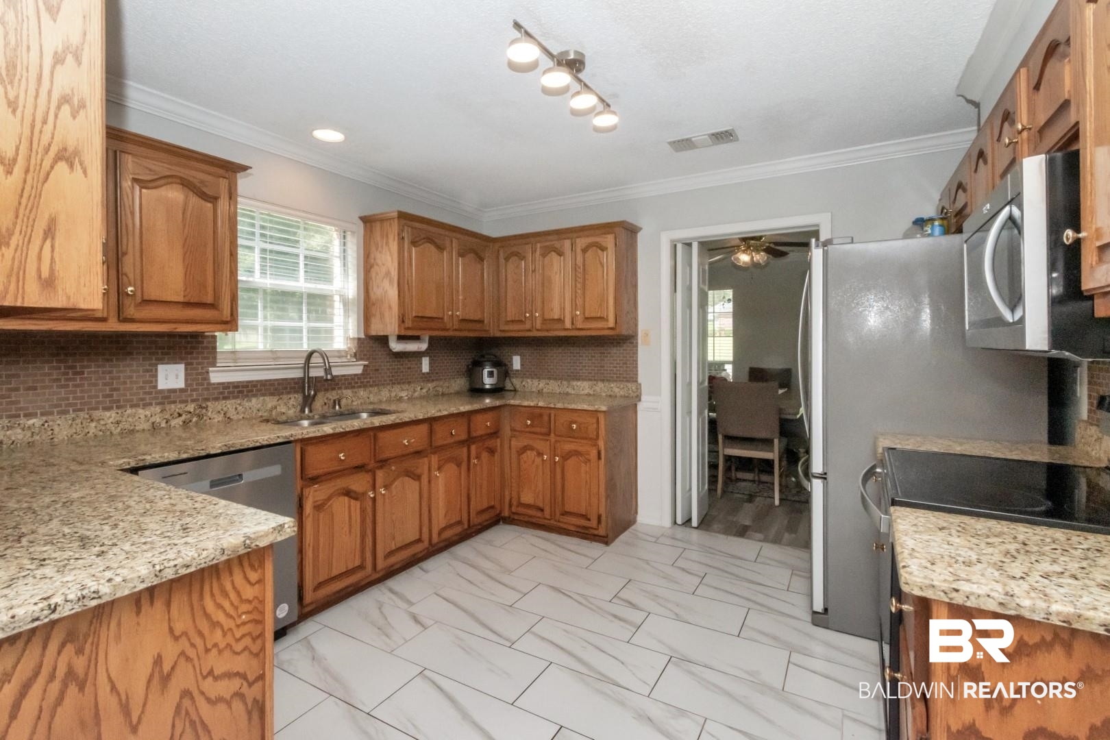 9991 Wedgefield Court Mobile, AL 36608 - Photo 6 of 30 Kitchen with appliances with stainless steel finishes, light tile patterned floors, decorative backsplash, and ceiling fan