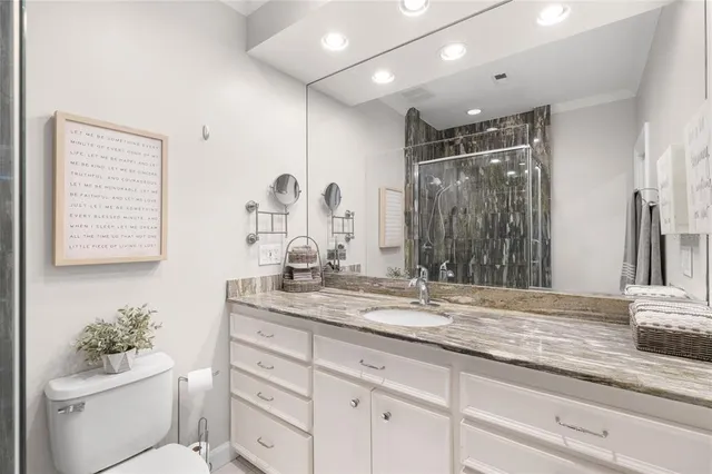 a bathroom with a granite countertop sink mirror vanity and toilet