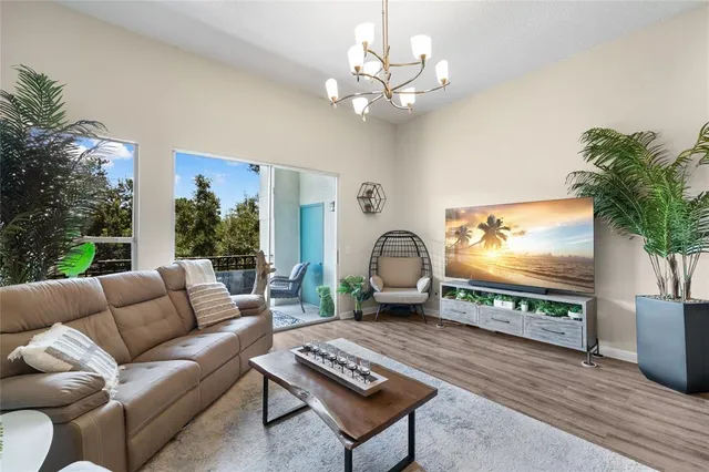 a living room with furniture a flat screen tv and a floor to ceiling window