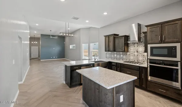 a kitchen with stainless steel appliances kitchen island granite countertop a refrigerator and a stove top oven