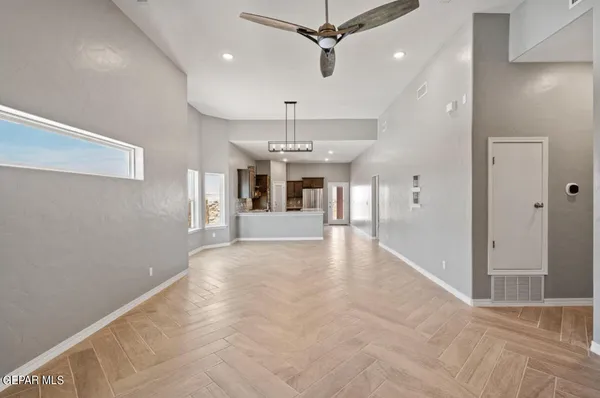 a view of a livingroom with a chandelier fan and kitchen view