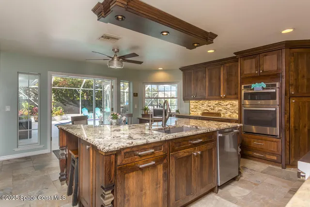 a kitchen with stainless steel appliances granite countertop a sink and a refrigerator