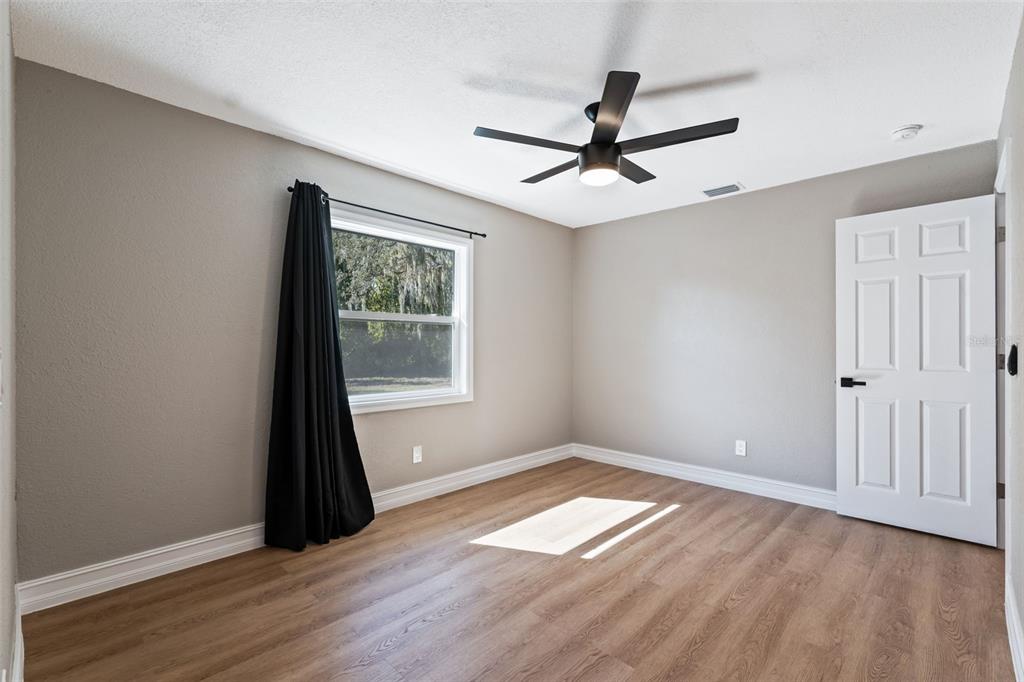 606 Kings Lane Southwest Winter Haven, FL 33880 - Photo 16 of 50 a view of empty room with wooden floor and fan
