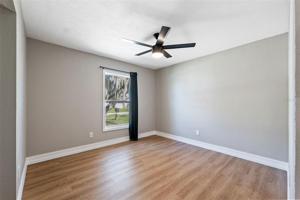 606 Kings Lane Southwest Winter Haven, FL 33880 - Photo 19 of 50 an empty room with wooden floor fan and windows