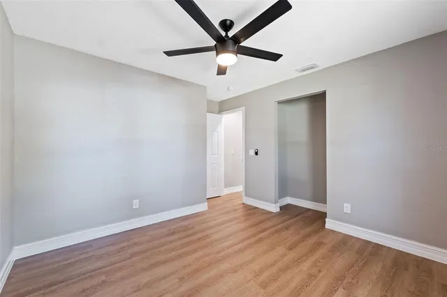 an empty room with wooden floor and ceiling fan