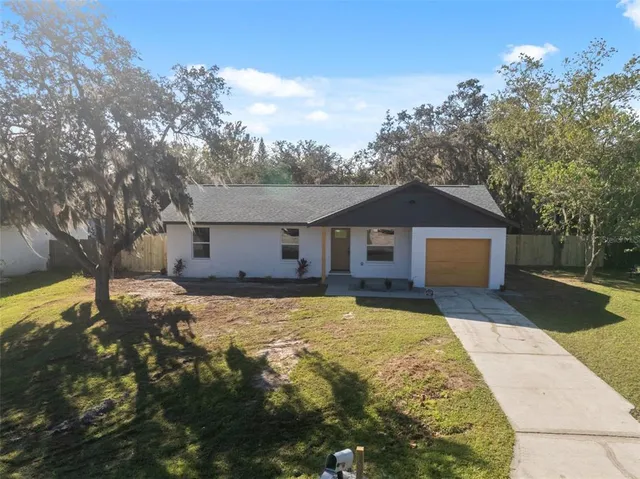 a front view of house with yard and trees in the background