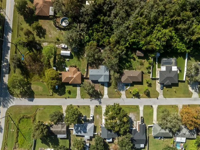 an aerial view of residential house with outdoor space and trees all around
