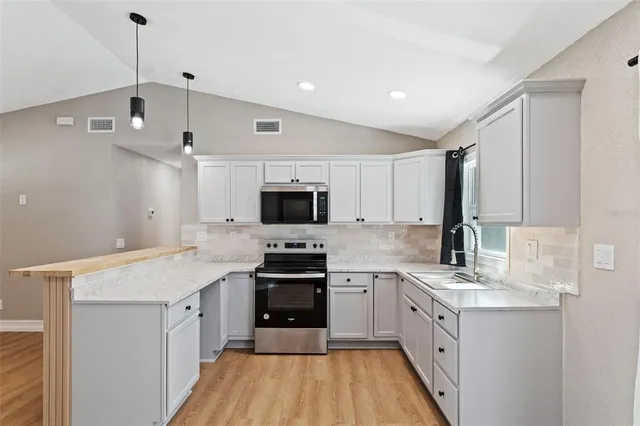 a kitchen with granite countertop a sink appliances cabinets and a counter top space