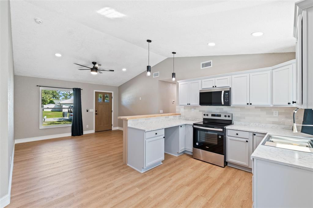 606 Kings Lane Southwest Winter Haven, FL 33880 - Photo 10 of 50 a large kitchen with stainless steel appliances granite countertop a stove and a sink