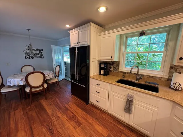 a kitchen with stainless steel appliances a sink a stove a refrigerator cabinets and dining table