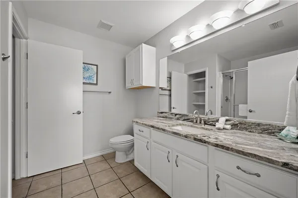 a en suite bathroom with a granite countertop sink and a mirror