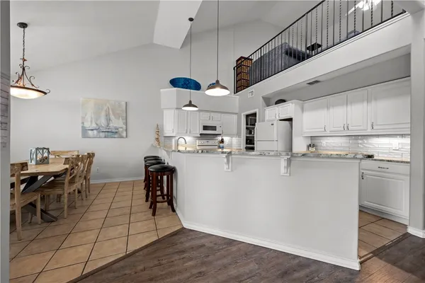 a kitchen with stainless steel appliances granite countertop a table chairs refrigerator and microwave