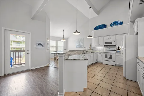 a large white kitchen with granite countertop a stove a sink dishwasher and a refrigerator