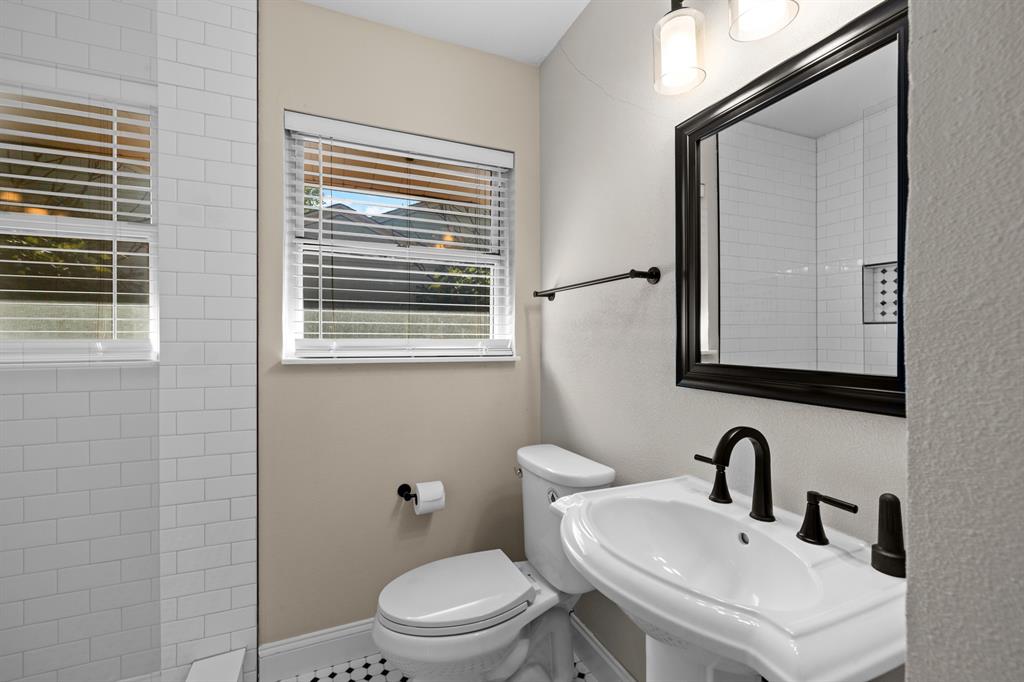 6317 Ravendale Lane Dallas, TX 75214 - Photo 10 of 16 a bathroom with a toilet a sink a mirror and a window