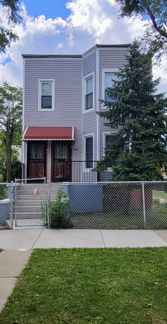 a view of house with a yard and a large tree