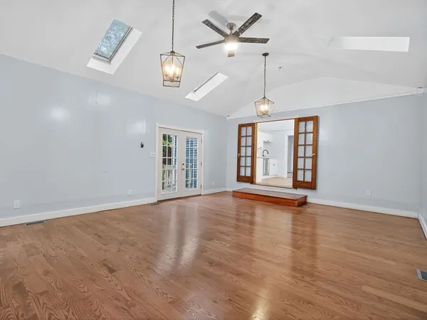 a view of an empty room with wooden floor and a window