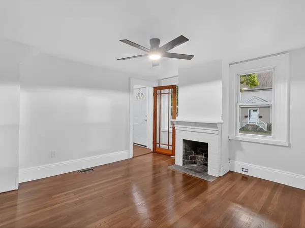 a view of empty room with wooden floor and fireplace
