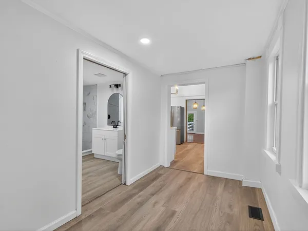 a view of a hallway with wooden floor and a bathroom